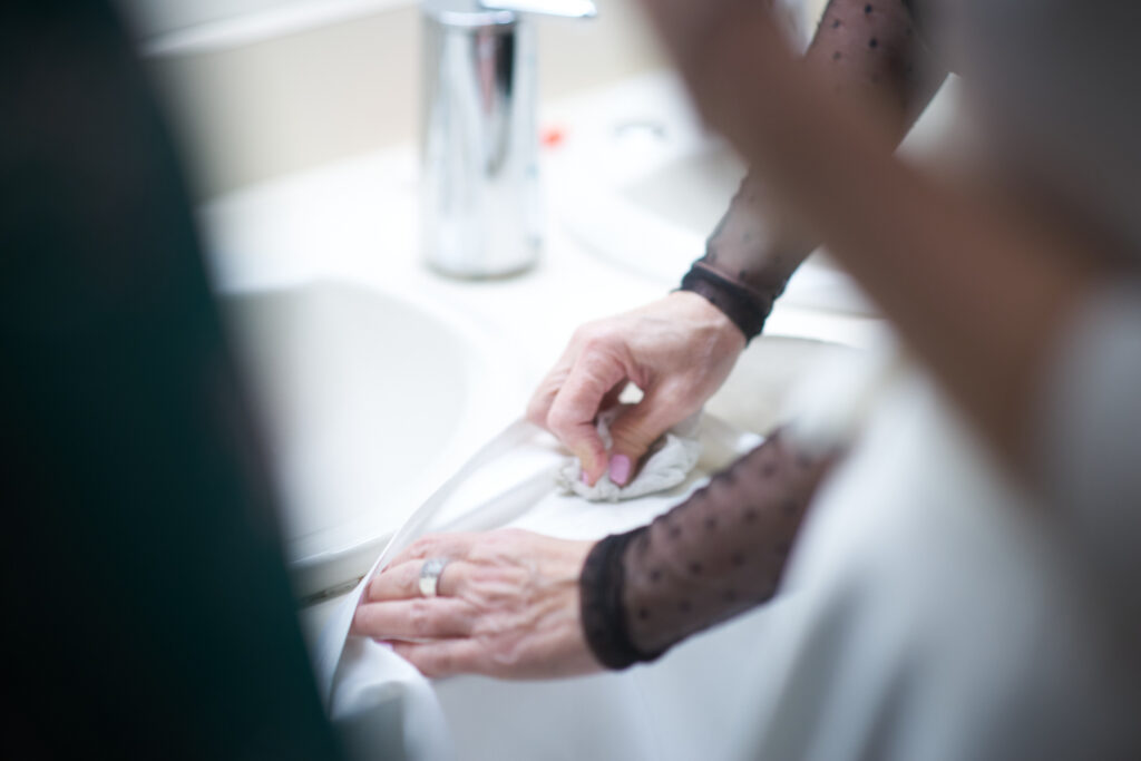 The hands of the bride's mother scrub a stain out of the wedding dress.